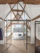 Steel-and-glass doors connect the bedroom to an en suite bath with a freestanding tub.