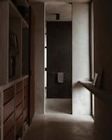 In the primary suite, a walk-in closet leads to a moody bathroom with a concrete sink.