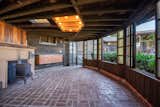 Special club house room with brick floor and wood-burning stove  Photo 9 of 9 in A Bernard Maybeck–Influenced Home With an Expansive Deck and Sunroom Seeks $1.5M in the Bay Area