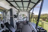The indoor/outdoor fitness area lets in fresh breezes and ocean views through a large, glass-panel garage door. The elevated structure has storage space below for garden/lawn equipment.