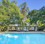 The rear of the home opens to a landscaped yard and large swimming pool.  Photo 13 of 13 in A Wood-and-Glass Midcentury by Craig Ellwood Lists for the First Time Since 1965