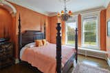 A rust-orange color scheme in another bedroom complements the dark wooden furniture and medium hardwood floors.