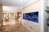 A built-in storage unit with an aquarium and concealed cabinets leads to the expansive kitchen.