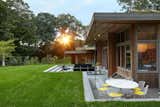 The sunken patio offers multiple partially covered gathering areas surrounded by the grass lawn.