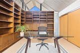 A room with clerestory windows and two walls of built-in bookshelves currently serves as an office.