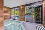 The serene, wood-paneled spa was added to the home in the 1980s. Large windows and sliding glass doors connect the space to the backyard swimming pool.  Photo 11 of 18 in A Respectfully Renovated “Super Eichler” Asks $2.5M in Walnut Creek, CA