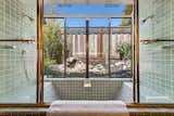 A tiled soaking tub and double shower overlooks the fenced-in side yard.  Photo 10 of 12 in $1.9M Will Land You This Tastefully Updated “Pop-Top” Model Eichler in the Bay Area
