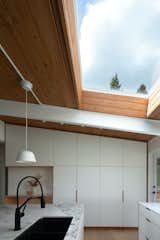 An oversize island with a marble countertop sits below a large skylight.&nbsp;