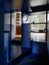 Houses with a closed-off stair room, such as this North London flat, can use dramatic colors to create a memorable passageway. Patalab Architects turned a strange transitional space into a striking stairwell by replacing a wall section with open shelving to allow more daylight, painted the stairwell in a blue from Dulux, and painted SLV Plastra wall lights to make this stairwell pop.