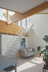Douglas fir laminated beams hover over the stairs that run from the top floor to the roof garden. The couch is by Sentou, while the chairs are from Vitra