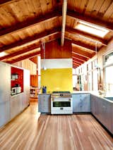A cutout in a wall in the kitchen creates a sight line to the living/dining room, which is overlooked by the art loft. The kitchen range is by Fulgor Milano, while the sconces are from Vipp.  Photo 4 of 12 in An Outdoorsy Family’s Bay Area Midcentury Gets an Era-Defying Update