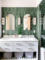 In the primary bathroom, Harlow sconces from Schoolhouse Electric hang above a double vanity from Restoration Hardware. The green subway tiles are from Nemo.