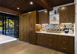 The concealed refrigerator/freezer blends in with the dark-wood cabinetry throughout the kitchen and bar area.