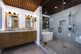 In the principal bath, a double sink vanity sits near a large, walk-in shower with a built-in seating nook and a freestanding tub.