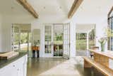 Glass-paneled doors connect the kitchen/dining area to the covered patio and surrounding lawn.