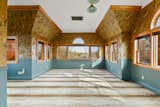 Another large room showcases funky wallpaper, blue-painted wainscoting, and patterned carpet.