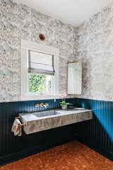 The listing features four bathrooms- three in the main home, and one in the guest house. Here, a playful nautical wallpaper is juxtaposed against a floating marble sink.
