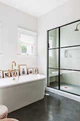A walk-in shower is decorated with subway tile, while a freestanding bathtub is adorned with vintage gold finishes.&nbsp;