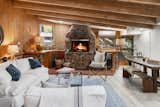 The living room hosts a slanted, exposed-beam ceiling and a massive stone fireplace.&nbsp;
