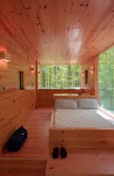 A queen bed sits next to one of three large windows. The lighting throughout is by Philips Hue Bulbs.