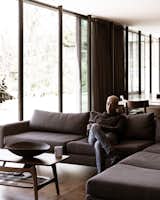 A narrow black hallway snakes through the house, connecting bedrooms to shared spaces like the living room, where Jorge catches up on his phone.