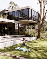 Dark finishes and industrial touches, such as the exposed steel structure on the second floor, are tempered by plentiful connections to out-door spaces, like the backyard, where Cony practices yoga.