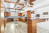 The kitchen features wooden cabinets, exposed beams, tiled floors, and a sky-blue backsplash.&nbsp;