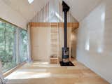 A simple living space features a minimalist fireplace, and a ladder leads to the bedroom area.&nbsp;