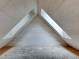Upstairs, two sizable windows light up the bedroom, which is framed by natural wooden floor and materials.&nbsp;