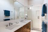 The primary bathroom hosts a double vanity with a long, horizontal mirror, and a walk-in shower.&nbsp;
