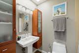 The bathroom attached to the second bedroom features two wooden shelves, a toilet, and a shower.&nbsp;