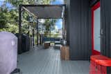 The deck follows the dark motif established by the home’s facade, with bright pops of red that echo the color of the garage door.
