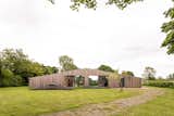 On a grassy knoll in the English countryside, the primary home sits secluded amoung the plants and trees.  Photo 2 of 19 in The British Countryside Is Calling in This Tranquil $2.8M Home