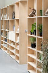 The hallway features abundant built-in shelving crafted from natural wood.&nbsp;