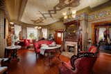 The ceiling of the living room features an ornate pattern, one of several found throughout the rest of the home. An original fireplace anchors it all.