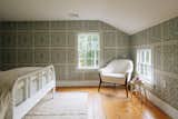 The secondary bedroom is decorated in a lovely green Victorian wallpaper, complimented by white-framed windows and baseboards.&nbsp;