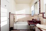 The en suite bath to the primary bedroom is richly colored in maroon, peach, and white.