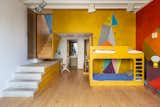 The colorful ground floor hosts an indoor rock climbing wall, a bathroom, and a laundry room.