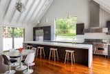 An elongated, marble waterfall island anchors the open kitchen, which is located just steps away from the primary living spaces.