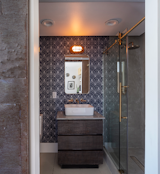 Patterned wallpaper surrounds a large shower in one of the three full bathrooms.