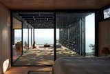 The guest bedroom feels private without being closed off, thanks to ample glazing. “Our houses are skeletons with windows,” says Manieu.  Photo 1 of 10 in garden by Rodriguez from A Surfer Couple Build an All-Black Off-Grid Cabin on a Seaside Bluff in Chile