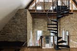 Lofted above the great room is a vaulted atelier that features a spiral staircase and a material mix of stone, steel, and wood.&nbsp;