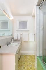 Original patterned tile awaits in the primary bathroom, along with a seafoam-green tub.&nbsp;