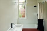 The en suite bath for the main bedroom features black fixtures and fittings that pop against white wall tiles.