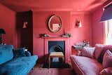 A blue velvet sofa adds colorful contrast in the all-pink living room located near the kitchen.