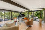 A large living area is encased in floor-to-ceiling glazing that opens to a wraparound deck.