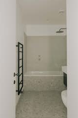 In the fully remodeled bathroom, black fixtures and fittings pop against Terrazzo tile.