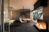 A contemporary entertaining space at the back of the house features a metal fire pit and a hanging bubble chair. This area leads to the detached studio guesthouse.