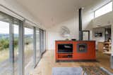 An orange wood stove serves as a colorful partition between the living and dining areas.
