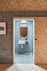 Martin and Casey wrapped the interior in oriented strand board. The rough-and-ready finish contrasts with the cool tones and polished surfaces of the bathroom, which is clad in Polarity terrazzo from Fibonacci. “It’s a minimal approach maximized,” Martin says.
